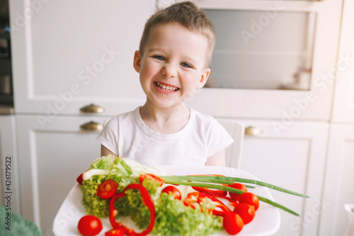 Cute boy preparing a salad of fresh vegetables. Boy preparing a salad for his mother