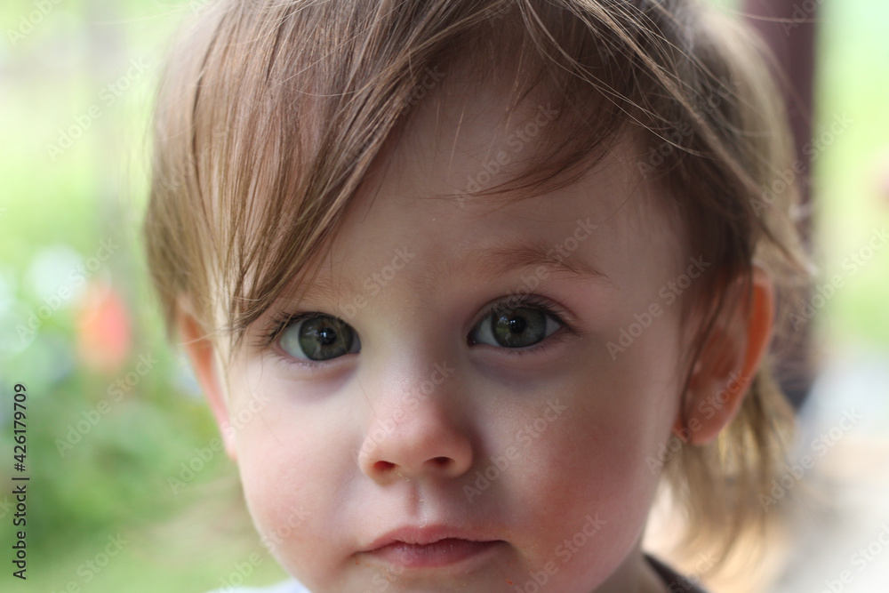 Close up photo of a small red-haired child with gray eyes looking at the camera Close up photo of a small red-haired child with gray eyes looking at the camera
