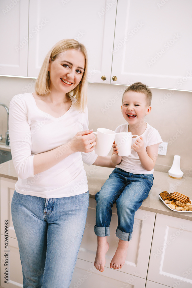 mom with little son in the kitchen eating cookies and drinking tea mom with little son in the kitchen eating cookies and drinking tea
