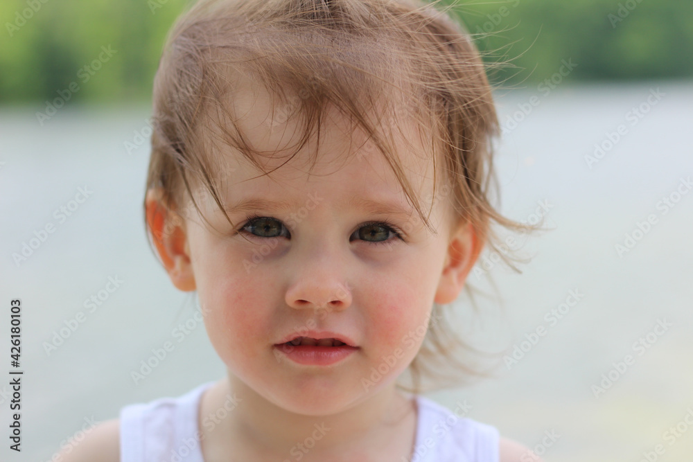 Cool little girl with gray eyes and short blond hair in a T-shirt on a blurred background of a city pond Cool little girl with gray eyes and short blond hair in a T-shirt on a blurred background of a city pond