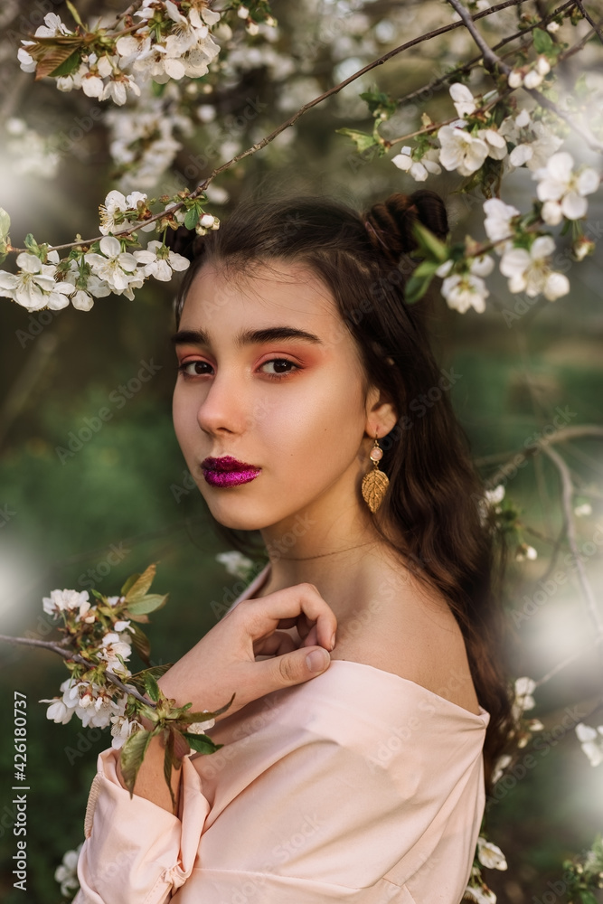 Beauty portrait redhead woman in spring in the branches of an apple trees Beauty portrait redhead woman in spring in the branches of an apple trees