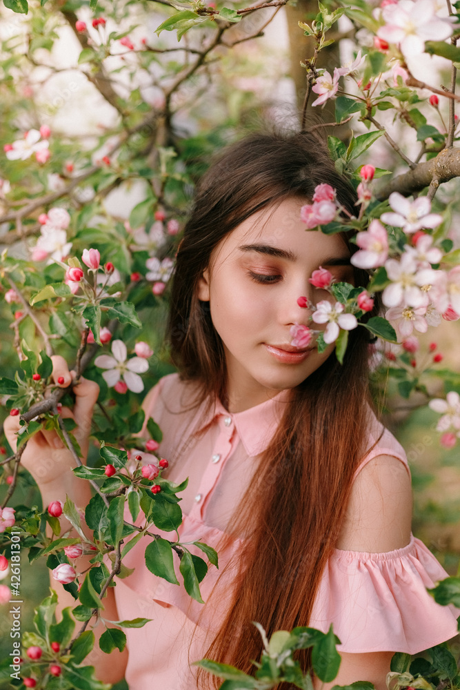 Beauty portrait redhead woman in spring in the branches of an apple trees