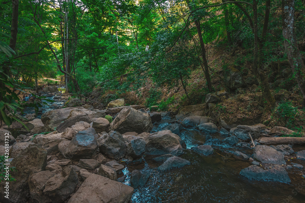 The wild landscape of a rivers with rocks. The river flows through the fall of the Velo de Novia waterfall. View of the rocks of the forest river in the ecological park The wild landscape of a rivers with rocks. The river flows through the fall of the Velo de Novia waterfall. View of the rocks of the forest river in the ecological park