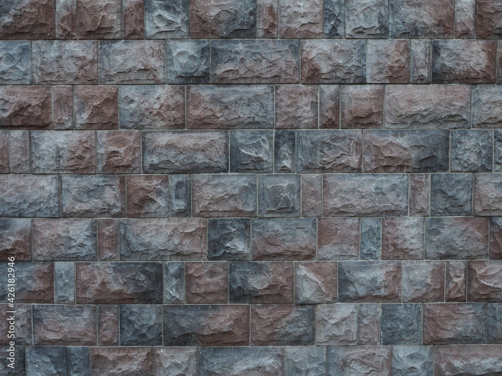 Wall with embossed brown gray granite tiles. Not seamless texture. Fullscreen photo