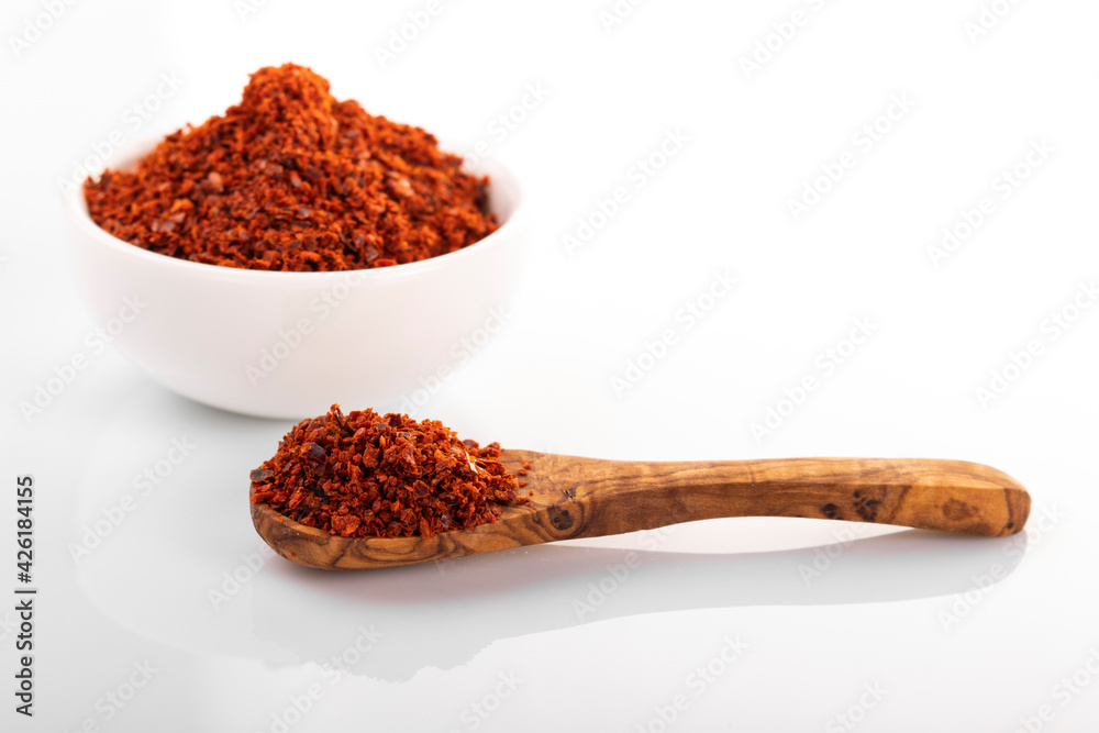 Korean hot pepper flakes. Pepper flakes in white bowl, with wood spoon, on white background Korean hot pepper flakes. Pepper flakes in white bowl, with wood spoon, on white background