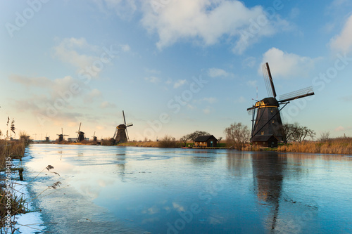 Windmills at Kinderdijk, close to Rotterdam in The Netherlands, in winter with ice on canal at sunset.