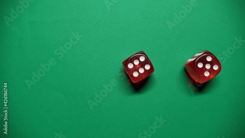 Red dice falling on green table. The Numbers 6 and 5 Appear on the Dice.