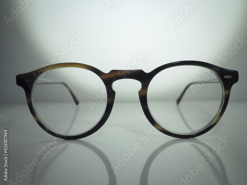 Rounded eyeglasses on a glossy surface