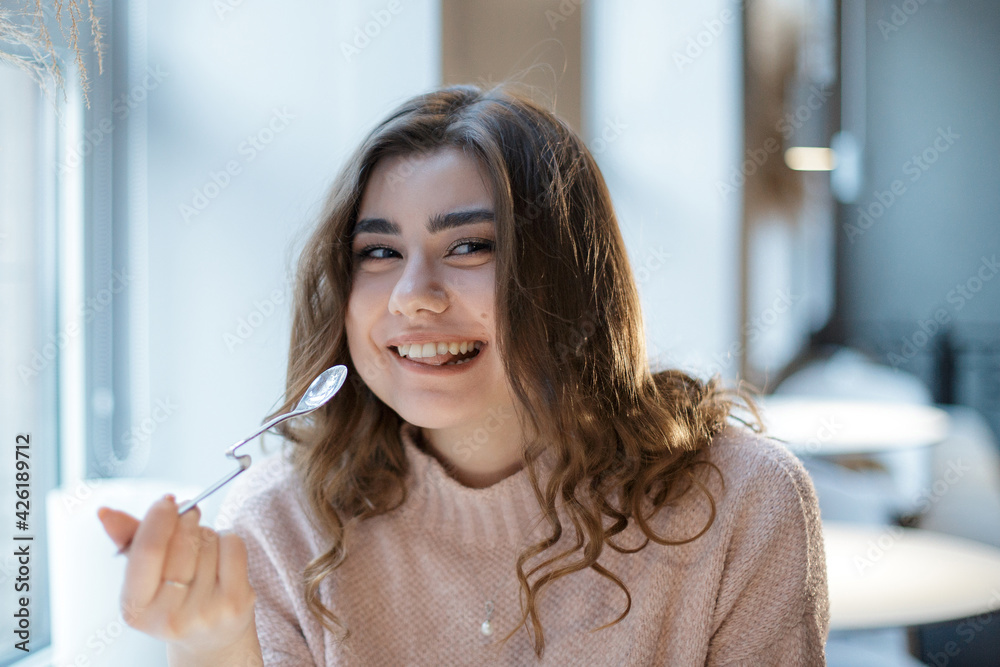 Beautiful young woman happy smiling sitting in restaurant or cafe and eating ice cream. Beautiful young woman happy smiling sitting in restaurant or cafe and eating ice cream.