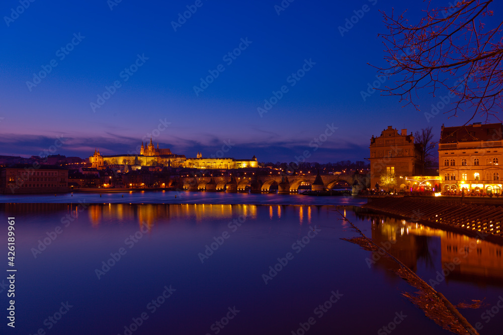 Prague at night along the river with Cathedral and Castle lit up (Czech Republic)