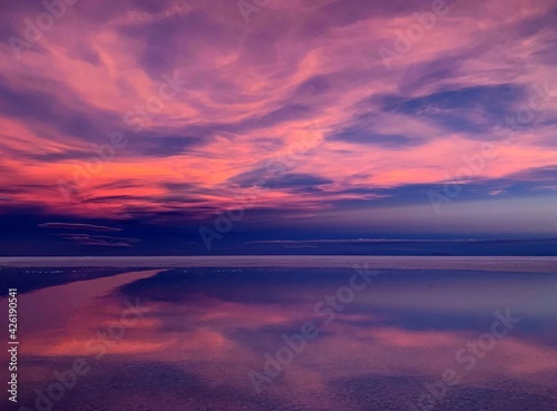 Sunset sky purple clouds shiny sea reflection. Divine sunset heaven. Magical alien landscape of planet. Space Martian nature. Mysterious lake horizon. Incredible desert view.