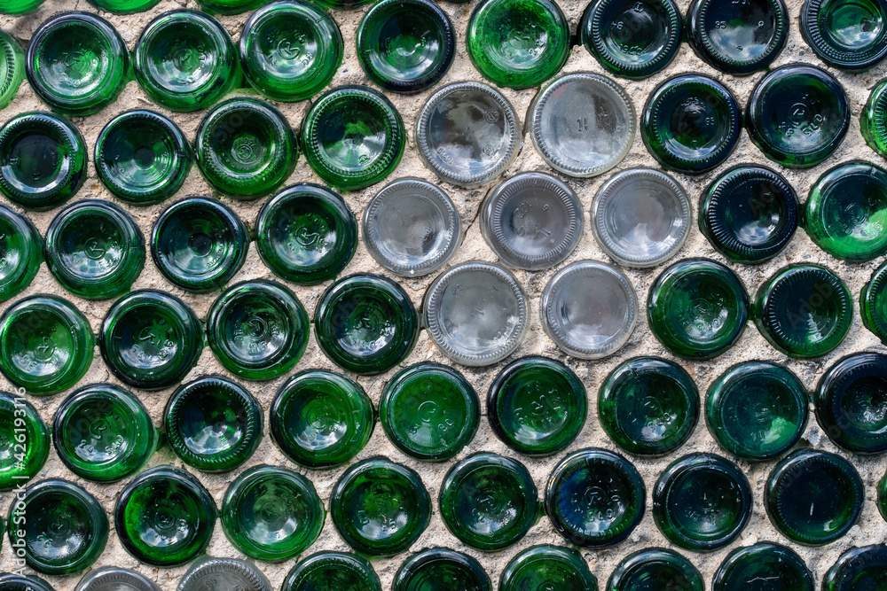 Wall of the house is made of used green and white glass bottles. Creative background. Wall of the house is made of used green and white glass bottles. Creative background.
