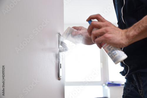 man hand cleaning desinfected metallic door handle door knob with the paper tissue and desinfection spray against the virus photo