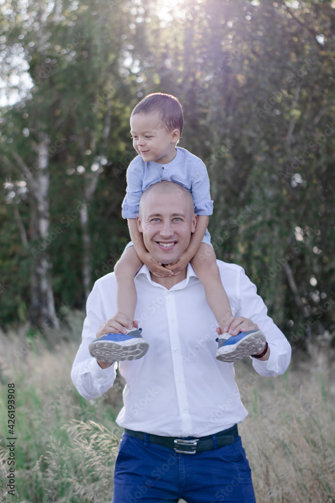 Obraz premium Bald dad and little son in the field or forest on sunny summer day. father's day.