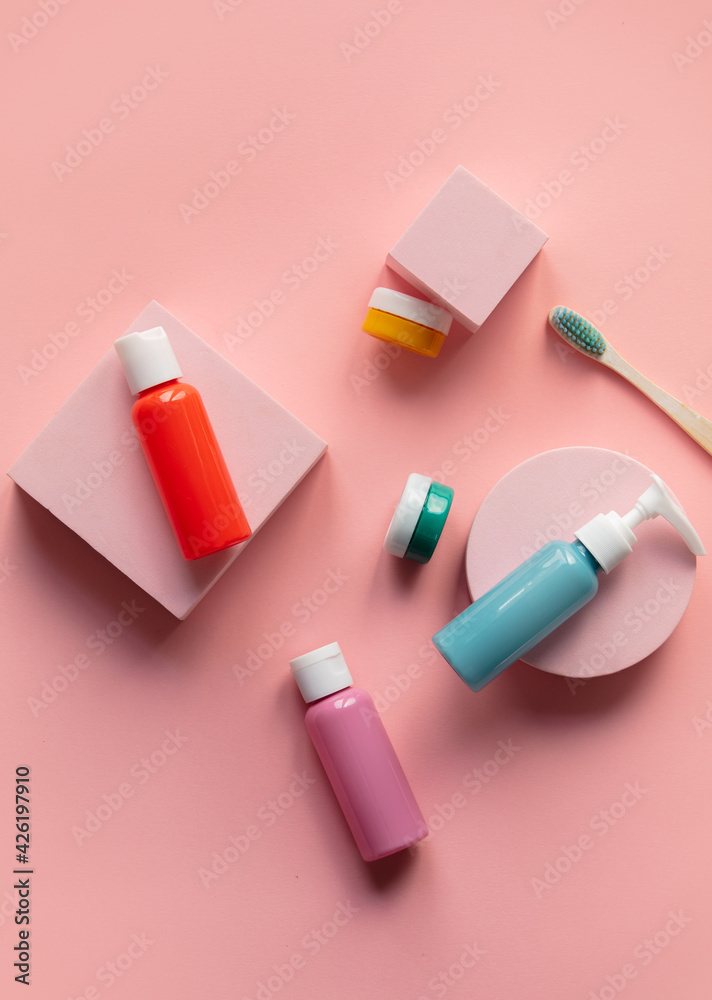 multicoloured bottles and jar with toothbrush on pink background multicoloured bottles and jar with toothbrush on pink background