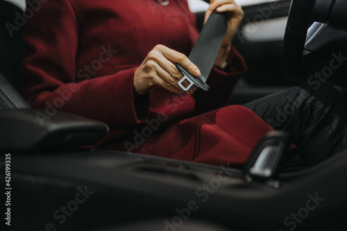 Close-up image of woman putting seat belt on before driving.