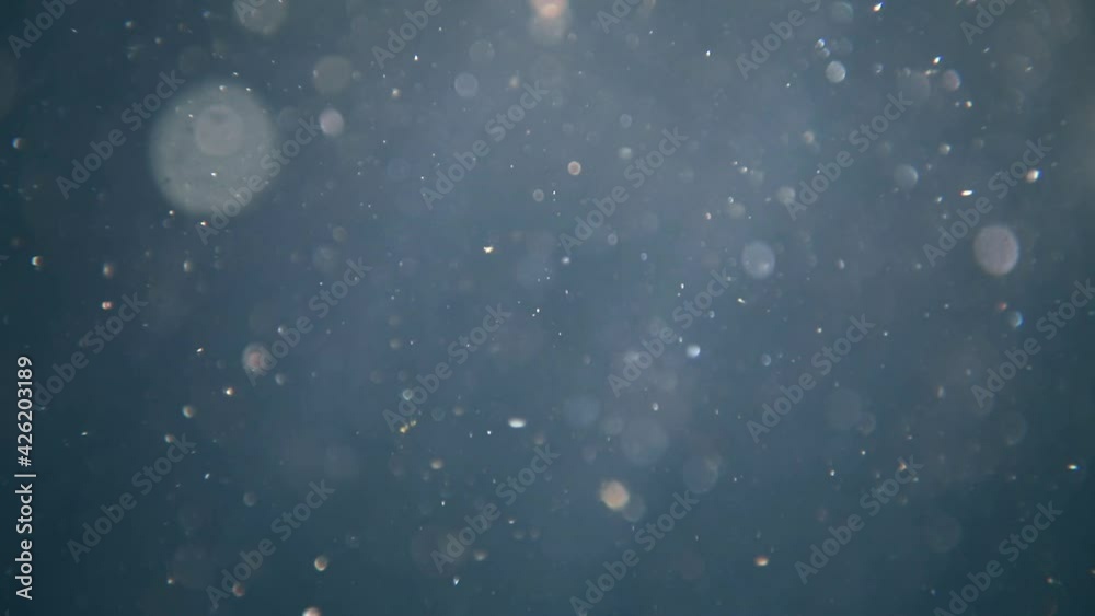 blue underwater background with sun rays and bokeh particles