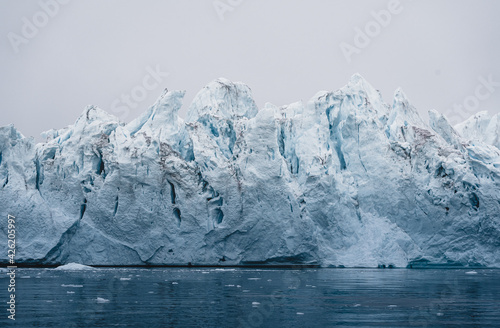 Arctic nature landscape with icebergs in Greenland icefjord with midnight sun sunset sunrise in the horizon. Early morning summer alpenglow during midnight season. Ilulissat, West Greenland.