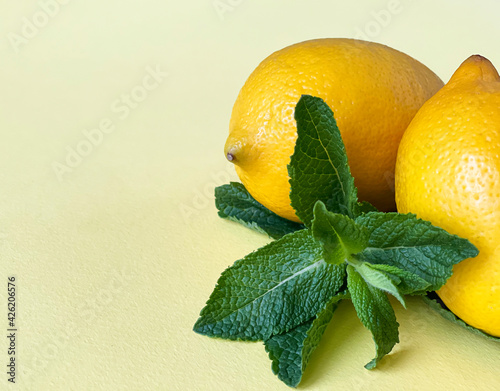 two lemons and mint on a yellow background