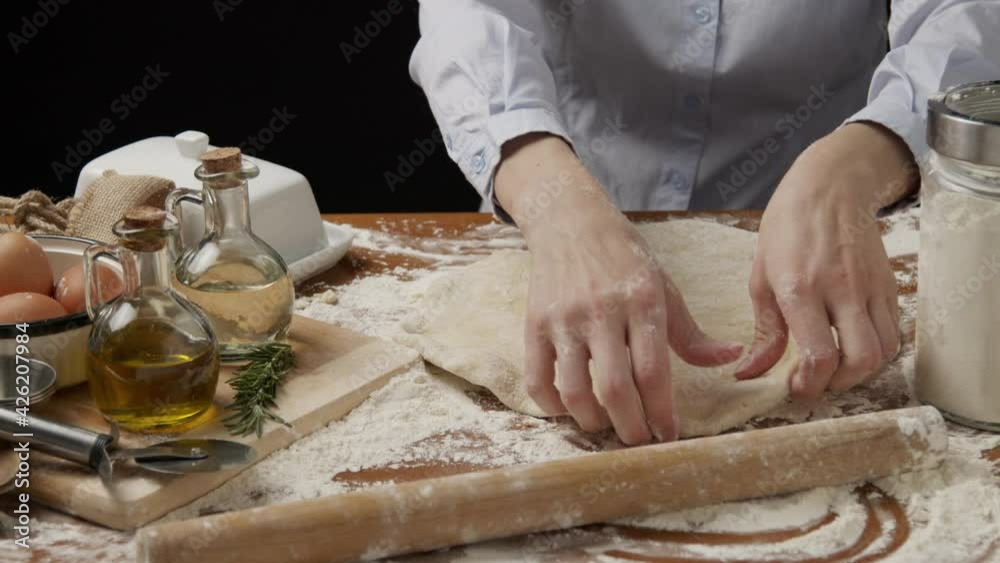 Kneading the dough. The process of making a delicious treat or dessert. Ingredients for baking on the table. Home cooking. Happy young woman wear apron kneading dough for pizza with hands flour baking Kneading the dough. The process of making a delicious treat or dessert. Ingredients for baking on the table. Home cooking. Happy young woman wear apron kneading dough for pizza with hands flour baking