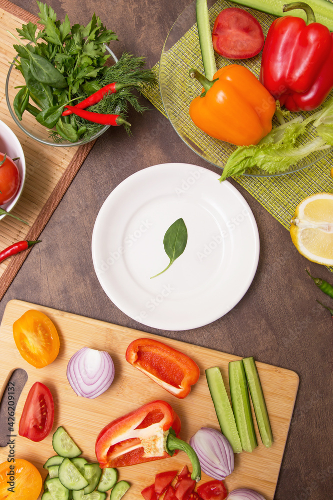 Different vegetables for cooking and one spinach green leaf on empty white plate. Diet, fasting, vegan, vegetarian, healthy food concept Different vegetables for cooking and one spinach green leaf on empty white plate. Diet, fasting, vegan, vegetarian, healthy food concept