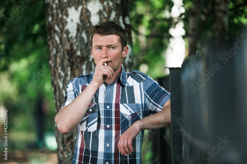 A smoking man portrait outdoors.