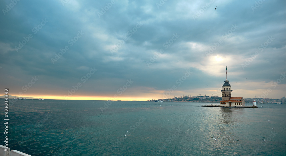The maiden's tower (kiz kulesi) istanbul, Turkey during overcast weather and sunset over bosporus sea. Groups of seagulls flying on sea. istanbul Turkey 01.03.2021