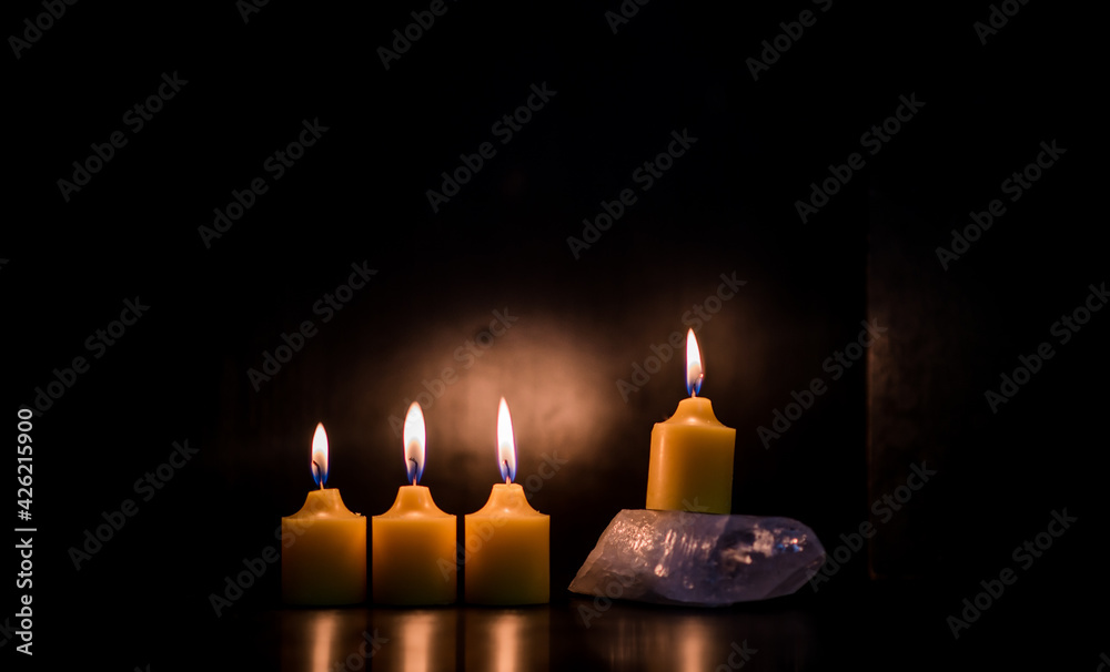 cuatro velas encendidas en fondo negro con cristal de cuarzo para  meditación foto de Stock | Adobe Stock