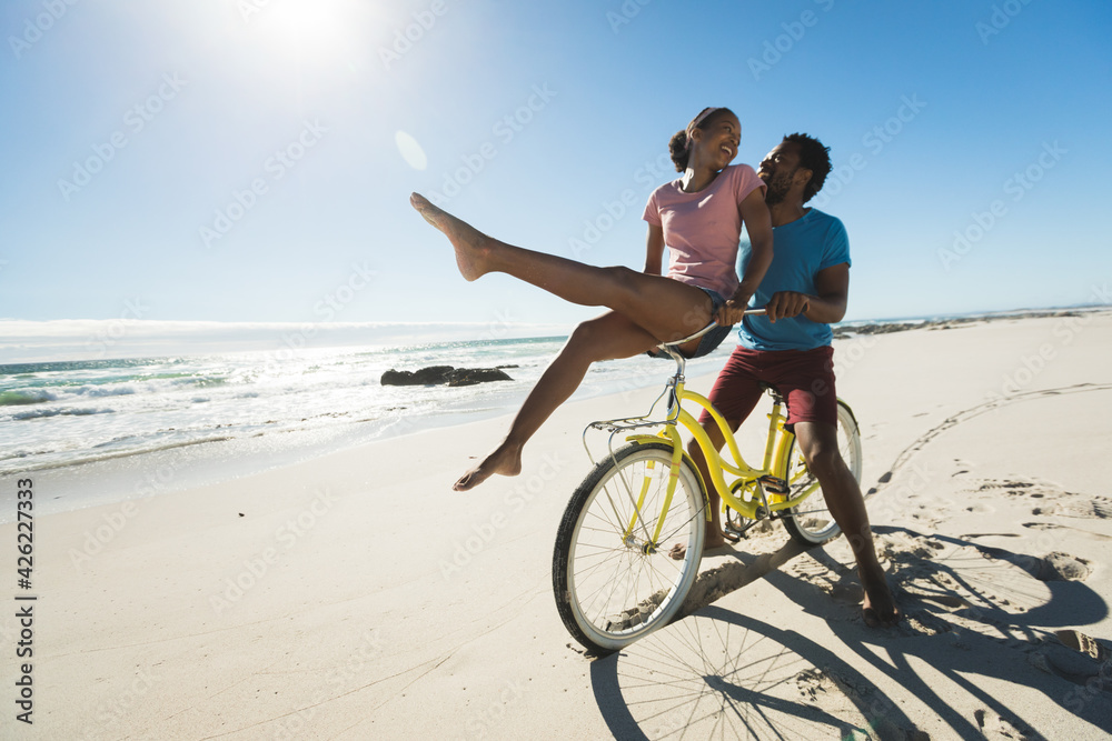 Happy african american couple riding bicycle on the beach Happy african american couple riding bicycle on the beach