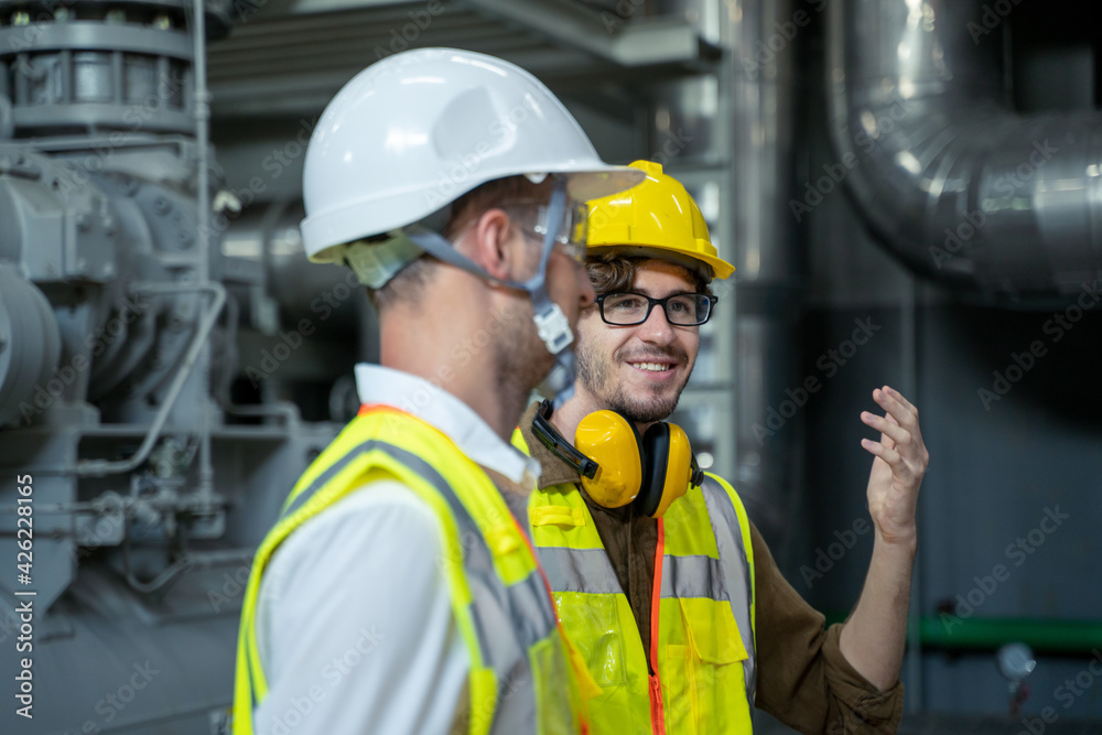 Industrial engineers discuss details with factory worker while using tablet computer working at heavy Industry Manufacturing Facility. Industrial engineers discuss details with factory worker while using tablet computer working at heavy Industry Manufacturing Facility.