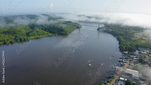 BINACIONAL DRONE AMAPA AMAZONIA DAWN WITH MIST BOAT ON THE OIAPOQUE RIVER DIVISES WITH FRENCH GUIANA