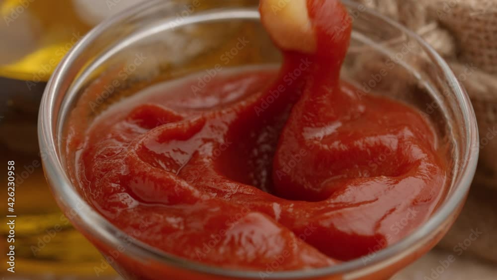 Close-up of womans hand dipping french fries in red ketchup sauce. Woman dials barbecue sauce on potatoes. Quick snack, unhealthy food or Breakfast. Close-up of womans hand dipping french fries in red ketchup sauce. Woman dials barbecue sauce on potatoes. Quick snack, unhealthy food or Breakfast.