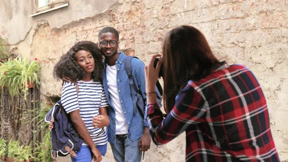 Young african american couple of tourists standing on background of old stone wall and posing for photographer. Young african american couple of tourists standing on background of old stone wall and posing for photographer.