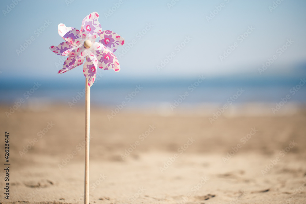 Toy windmill close-up on the background of sand of the sea and sky Toy windmill close-up on the background of sand of the sea and sky