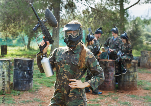Portrait of confident female paintball player with the marker gun ready for game outdoors
