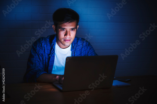 Fotografia Asian businessman working late night in front using computer laptop smart mobile
