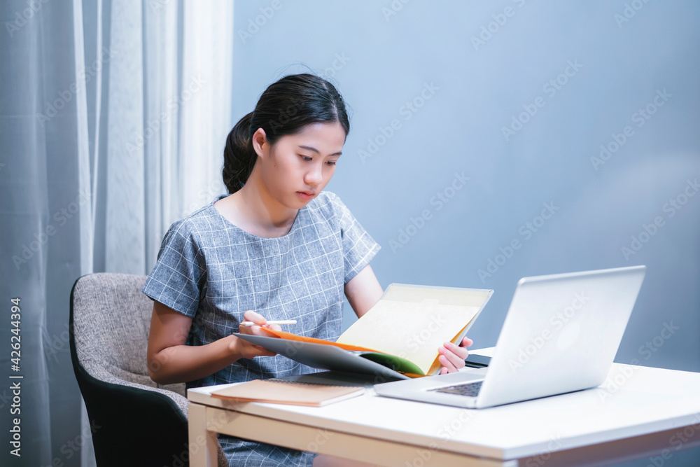 Asian businesswoman work from home office small business owner planning organizing strategy reading data in folder file, using smart tablet laptop computer technology information working late night Asian businesswoman work from home office small business owner planning organizing strategy reading data in folder file, using smart tablet laptop computer technology information working late night