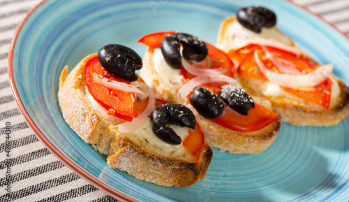 Breakfast toasts with melted cheese, tomatoes, onion and olives