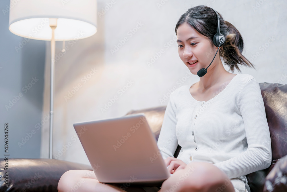 Asian attractive student girl happy smiling at home studying abroad online internet video call conference using computer laptop headset talking notebook study information lesson learning educational Asian attractive student girl happy smiling at home studying abroad online internet video call conference using computer laptop headset talking notebook study information lesson learning educational