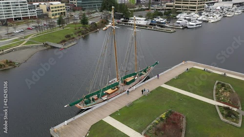 Cinematic aerial drone shot of a docked schooner sailboat by the Museum of History and Industry MOHAI at Westlake Park, looking from South Lake Union in Seattle, Washington photo