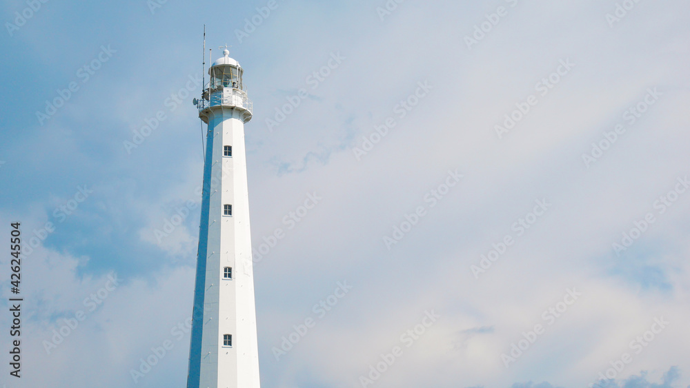Anyer, Indonesia-March 31, 2021: a historic lighthouse building that has a white color with several windows. The sky background is blue and there are colored clouds called the Mercusuar Cikoneng