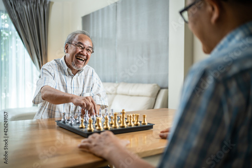 Asian old man enjoy playing chess together with friend in nursing home