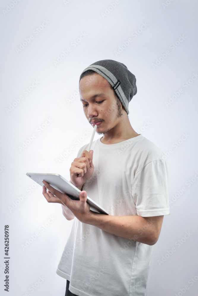 Image of Asian young businessman or designer with skullcaps holding and using a tablet isolated on white background Image of Asian young businessman or designer with skullcaps holding and using a tablet isolated on white background