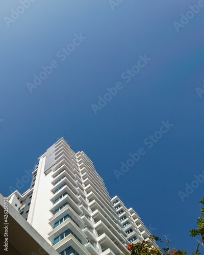 White and blue building exterior. low angle view of modern building under blue sky © ellinnur
