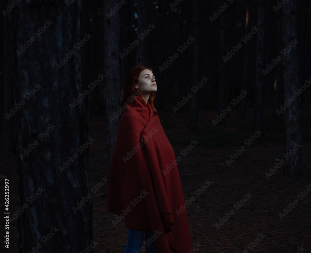 Beautiful woman with a red cape near the trees in the forest Beautiful woman with a red cape near the trees in the forest