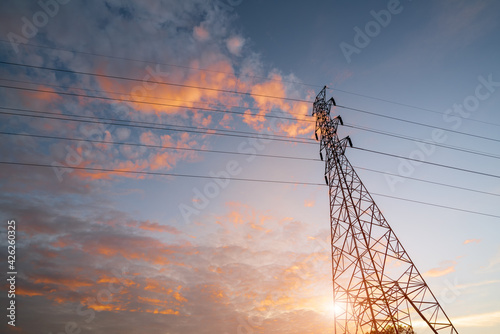 Electricity transmission power lines (High voltage tower) high-voltage lines. Transmission of electricity by means of supports through agricultural areas sunny day with landscape and sunset