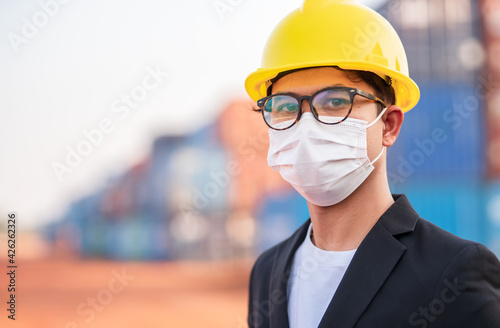 Closs up engineers managers or businessmen  Wear a safety helmet and mask on face to prevent the spread of Coronavirus covid-19 with container background.saffty and protection concept photo