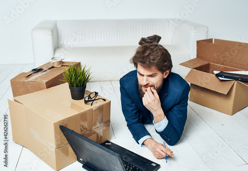 A man lies in front of a laptop boxes with things unpacking Office professional 