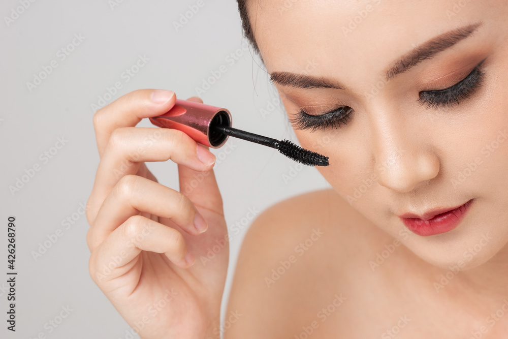 Close up face Asian woman applying mascara brush on eyelash. Applying cosmetic make up eyelash Extensions. Asian eye make up cosmetics.