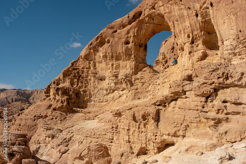 Female hiker posing at the Great Arch in Timna national park  southern Israel. Famous tourist attraction in the national park. Vacation in Israel. 
